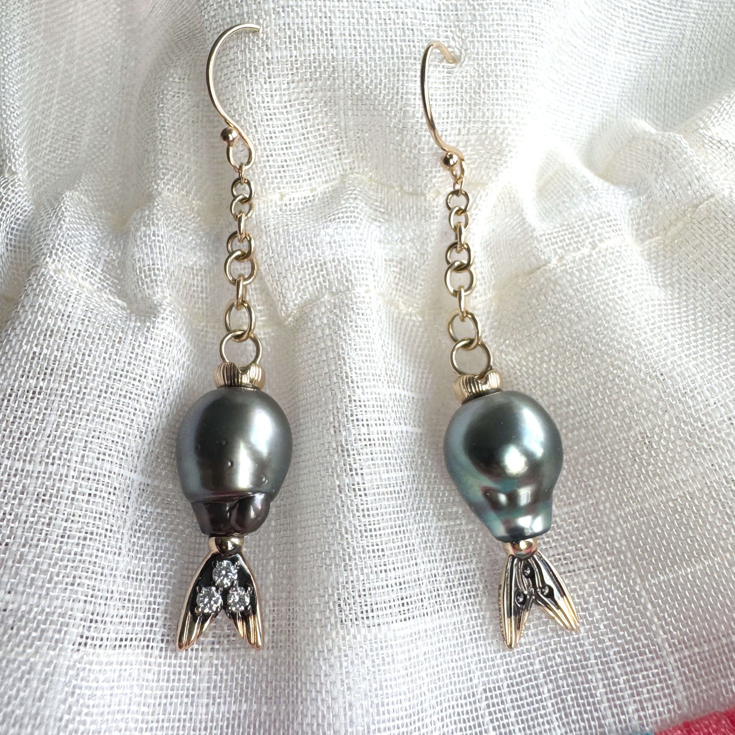 Pair of earrings with Tahitian pearls and gold accents on a white fabric background