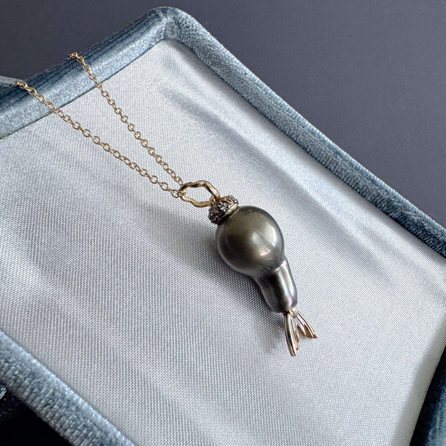 tahitian pearl pendant with diamonds in 14k gold on a gray fabric surface