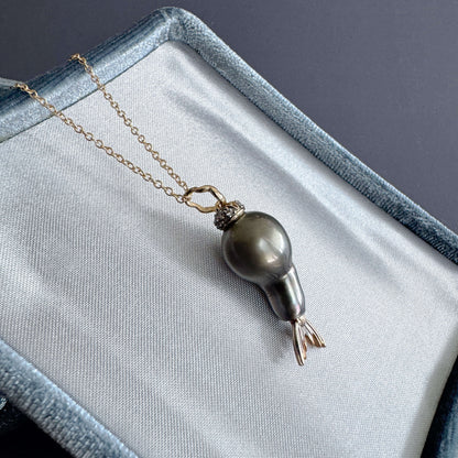 tahitian pearl pendant with diamonds in 14k gold on a gray fabric surface
