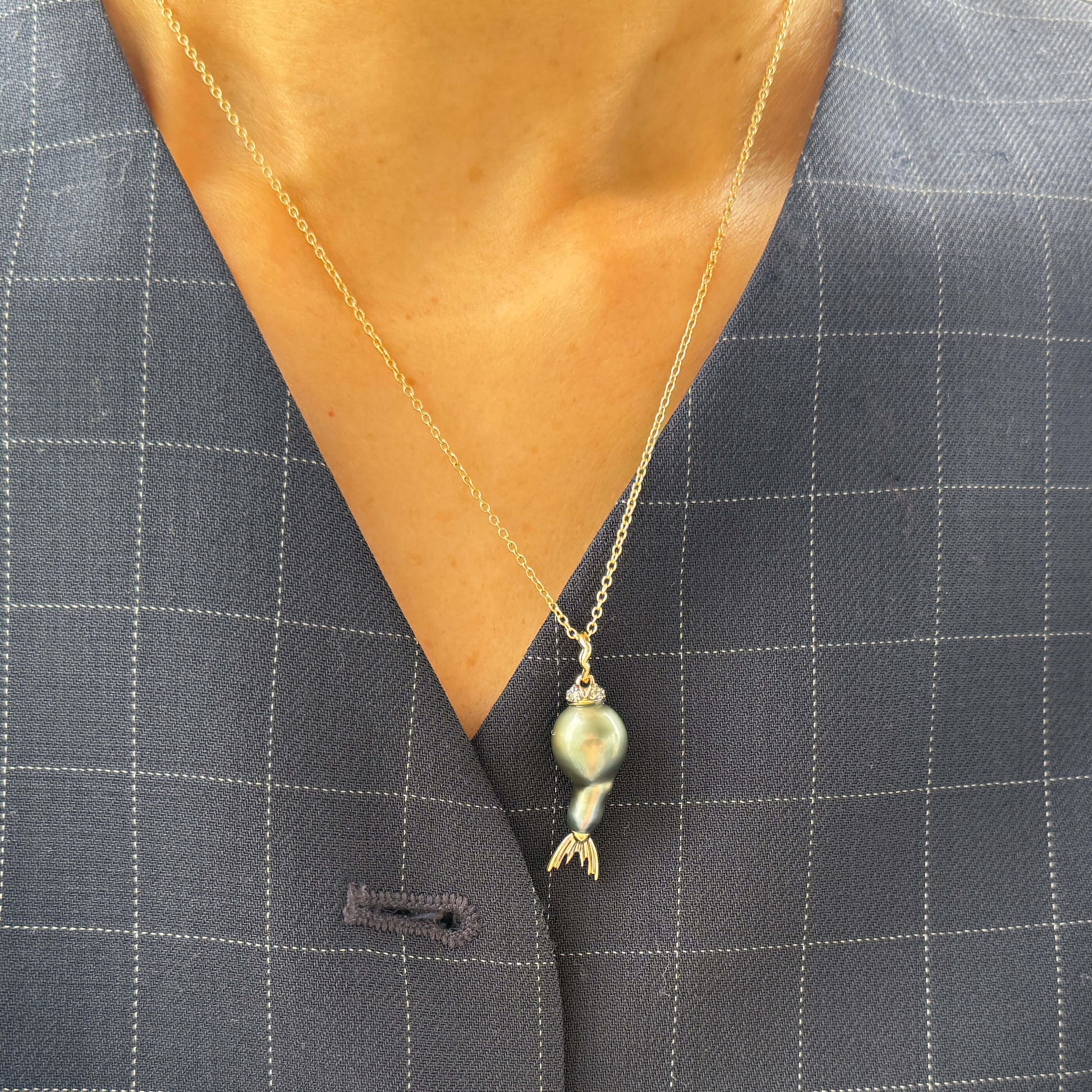 Tahitian pearl pendant with gold and diamond details on a gray suit jacket